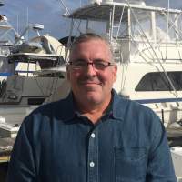 Gerald L. Kraaz standing in front of a boat