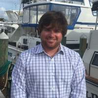 Taylor Beckford smiling and standing in front of boats